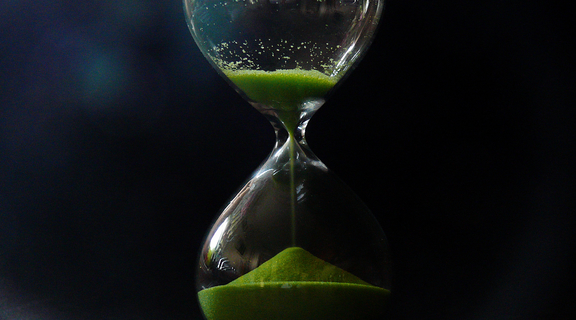 Homepage canva   hourglass with green sand on black background
